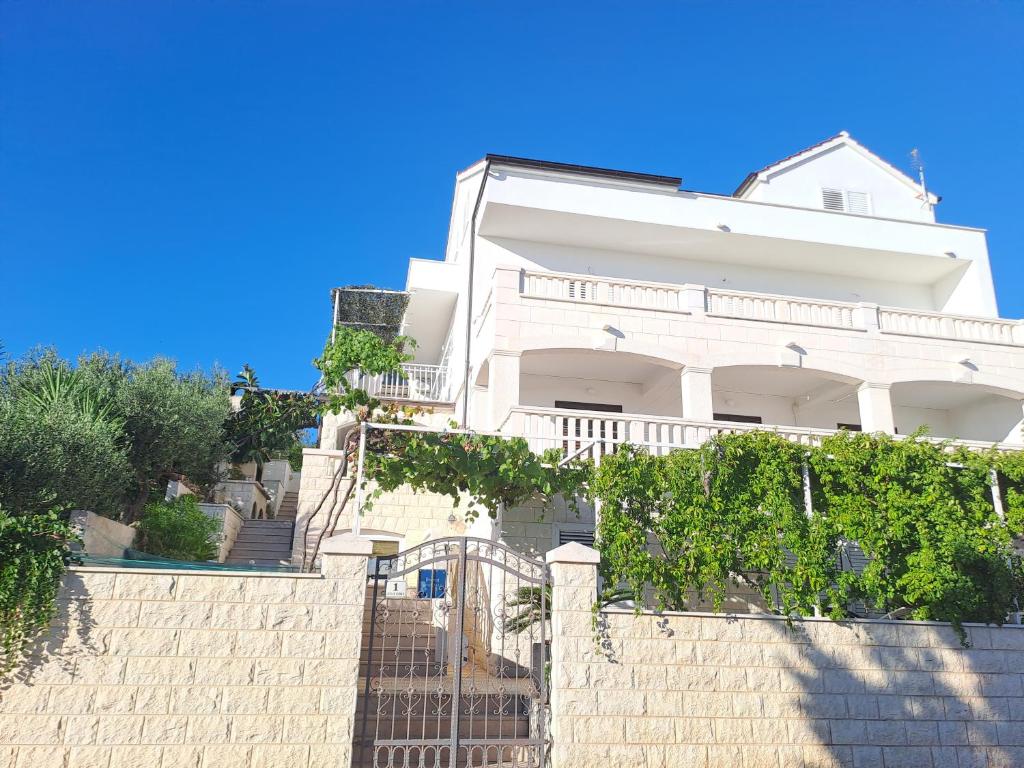 a white house behind a wall with a fence at Apartments Topo in Hvar