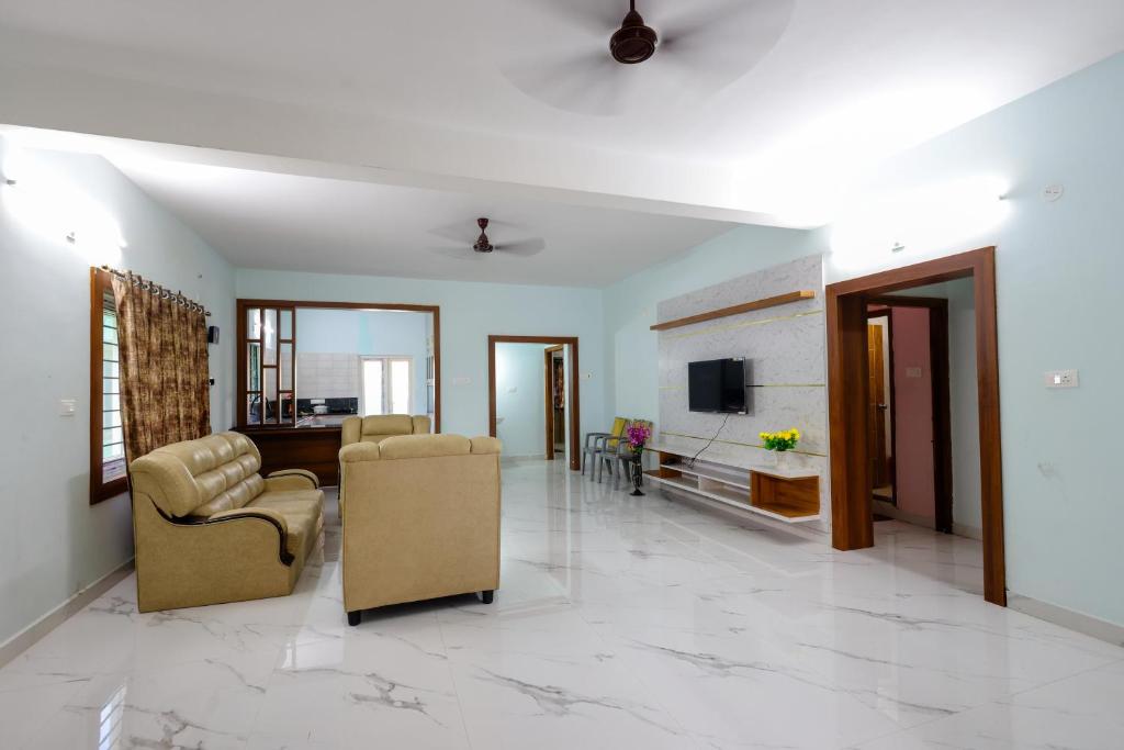 a living room with two chairs and a television at SBHS Narayanadri Homestay in Tirupati