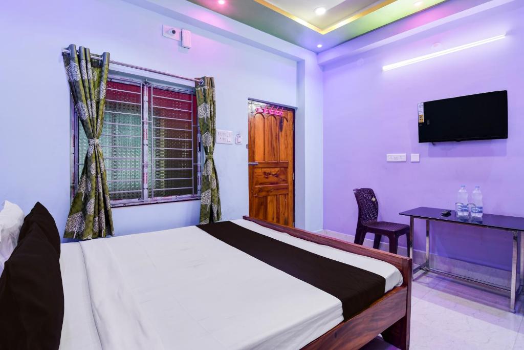 a bedroom with a bed and a desk and a television at Hotel O Subharaj palace 2 in Kolkata