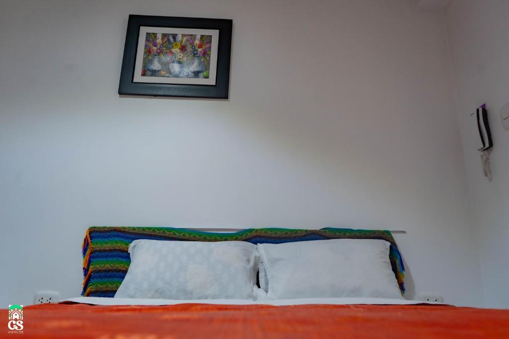 eine weiße Wand mit einem Bild über einem Bett in der Unterkunft GS Hoteles-Cajamarca in Cajamarca
