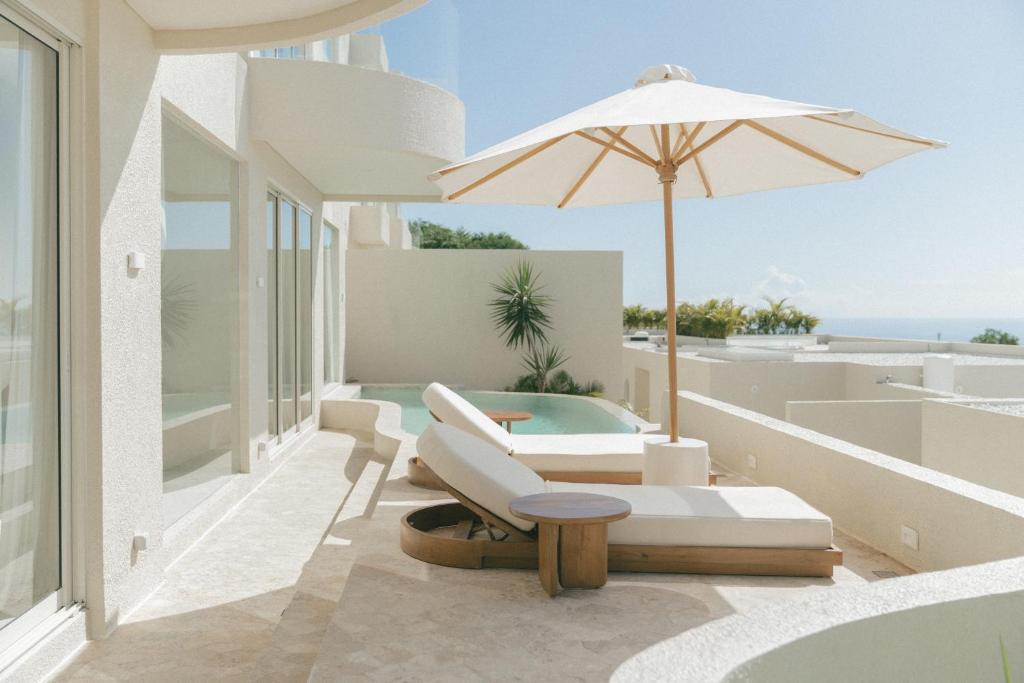 a patio with an umbrella and a pool at NOUR Uluwatu in Uluwatu