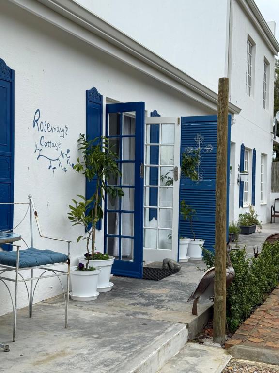 ein weißes Haus mit blauen Türen und Topfpflanzen in der Unterkunft Rosemarys Cottage in Koringberg