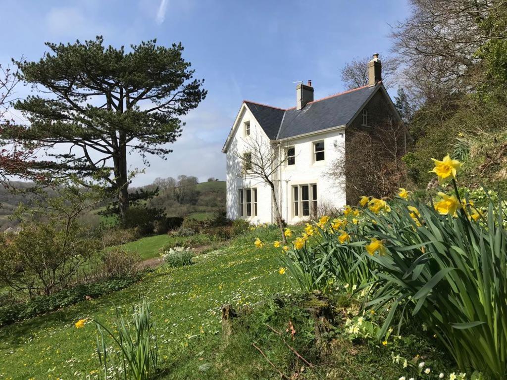 a white house on the side of a hill with flowers at 6 Bed in Branscombe oc-jbetco in Branscombe
