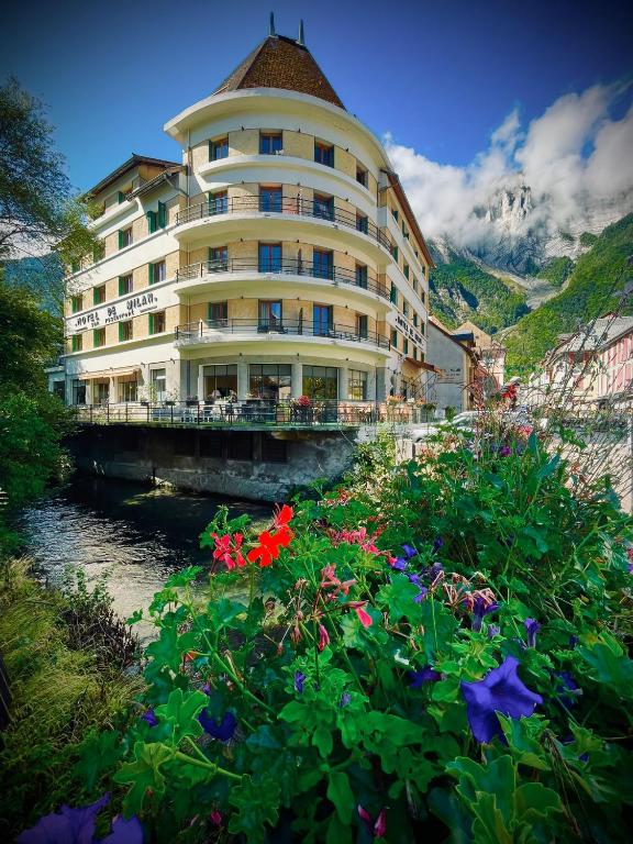 Hotel Sport'Hotel-Aparthotel de Milan, a large building with flowers in front of a river at Sport'Hotel-Aparthotel de Milan in Le Bourg-dʼOisans