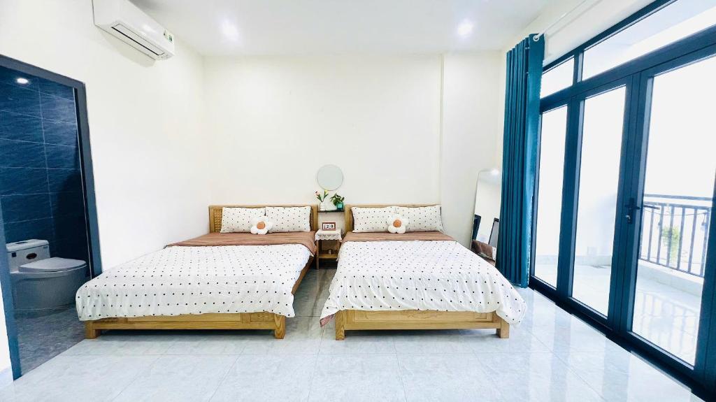 une chambre avec deux lits, une table et une fenêtre dans l'établissement 1988 Homestay Vũng Tàu, à Vung Tau