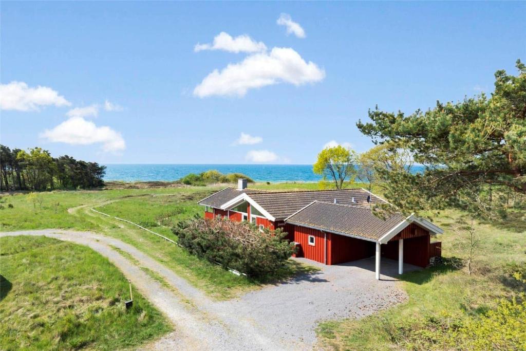a red house on a hill with the ocean in the background at 1416-Aakirkeby-Holsteroddevej-9 in Vester Sømarken