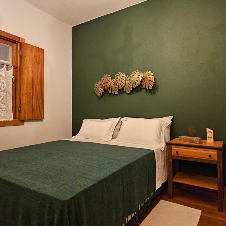 a bedroom with a bed with a green wall at CASA OURO até seis pessoas com conforto pertim do Centro Histórico in Tiradentes