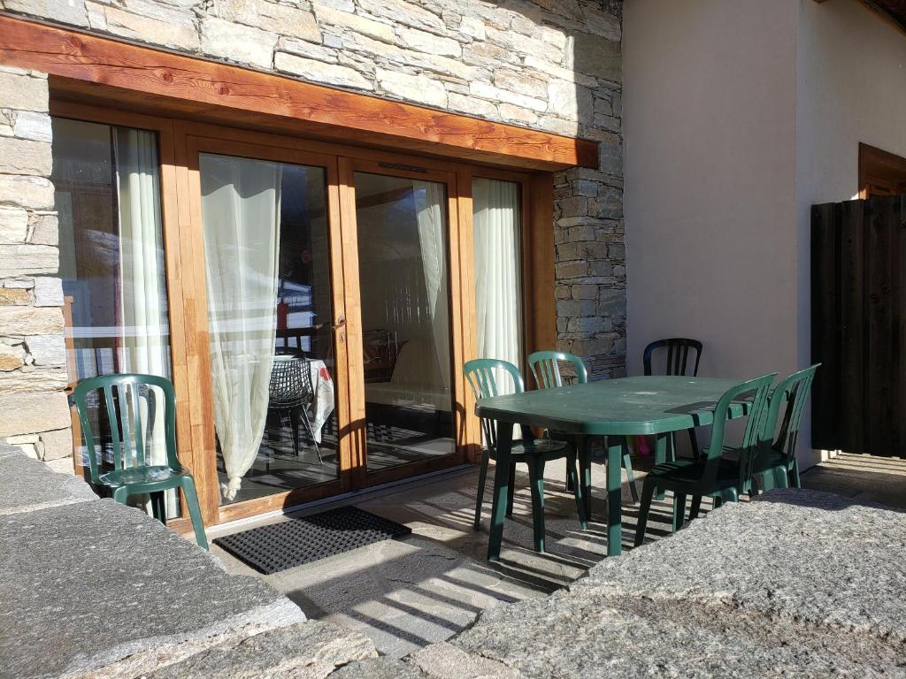 une table et des chaises vertes sur une terrasse dans l'établissement Critérium C02, à Les Champs