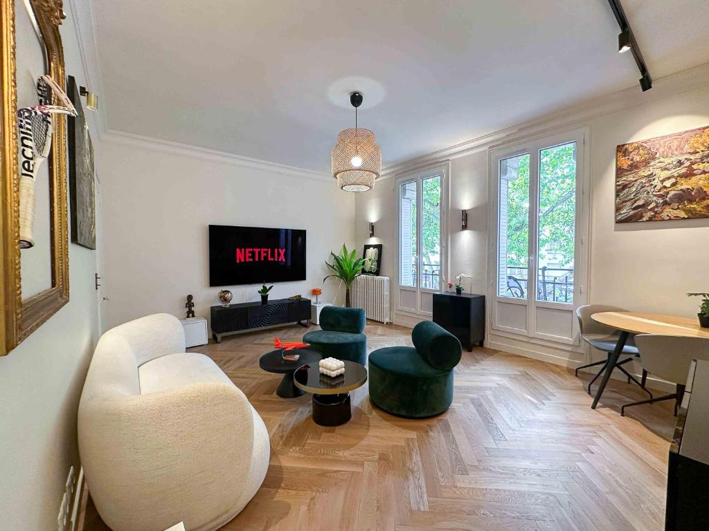 a living room with a couch and chairs and a tv at PARIS - Boulogne Résidence in Boulogne-Billancourt