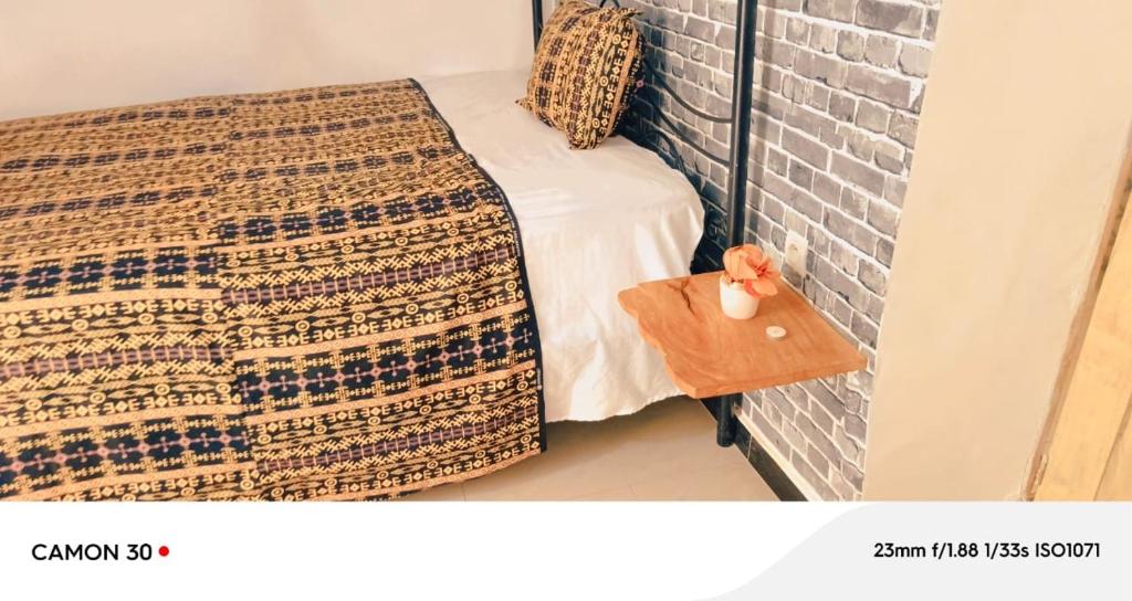 a bed with a blanket on it next to a brick wall at FARAFINA KEUR DAMEL Toubakouta in Toubakouta