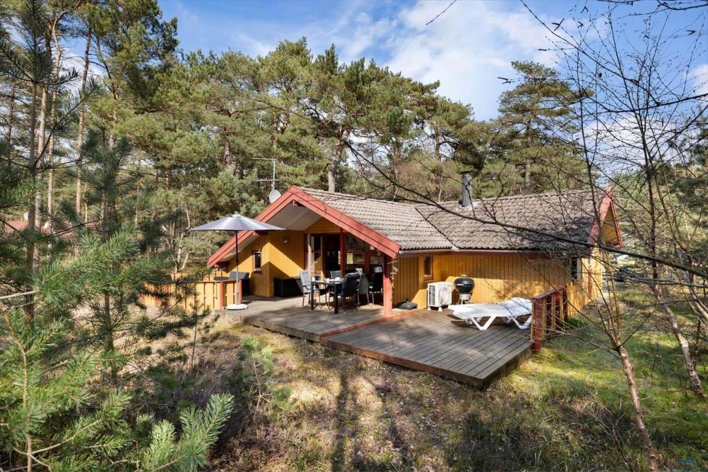 a cabin in the woods with a wooden deck at 2544-Nexo-Skovsangervej-29 in Neksø