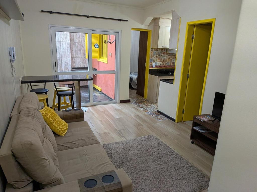 ein Wohnzimmer mit Couch und Tisch und eine Küche in der Unterkunft Apartamento central confortável in Pelotas