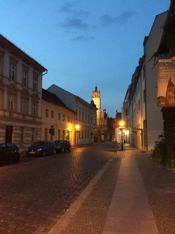 a city street at night with a clock tower at Rathaus-Pension 1685 in Brandenburg an der Havel