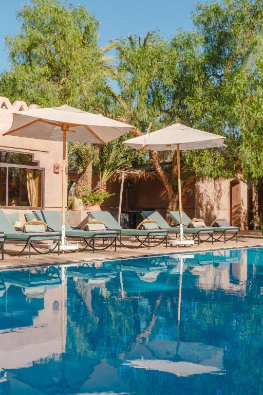 a swimming pool with umbrellas and chairs next to a swimming pool at Dar 55 - Berber House - Boutique Hôtel & SPA in Marrakesh