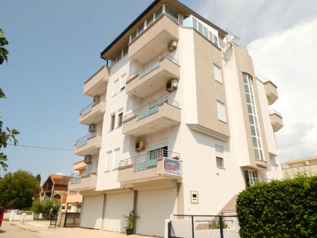 a tall white building with a fence in front of it at Apartments In Amor in Ulcinj