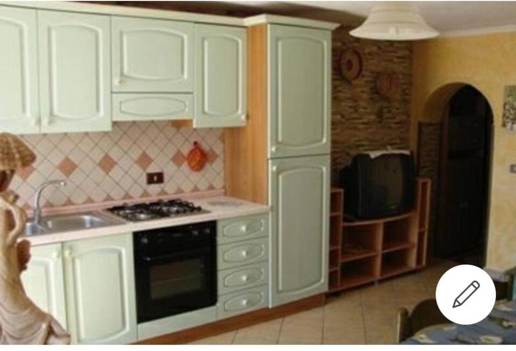 een keuken met witte kasten, een spoelbak en een magnetron bij Appartamento Mariolu 2 in Santa Maria Navarrese