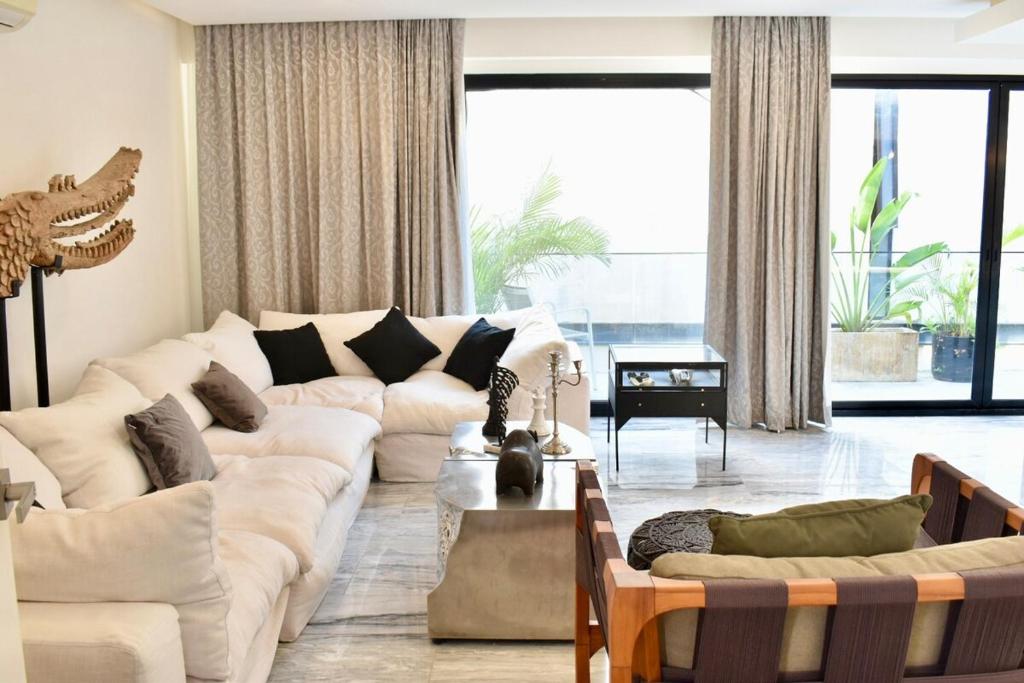 a living room with a white couch and a large window at Exclusivo 3 Hab, Terraza Privada, Alberca y Asador in Tulum