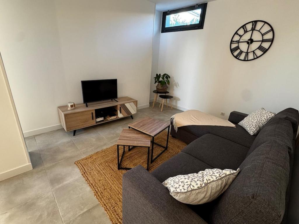 a living room with a couch and a clock on the wall at Entre Campagne et Ville in Marcorignan