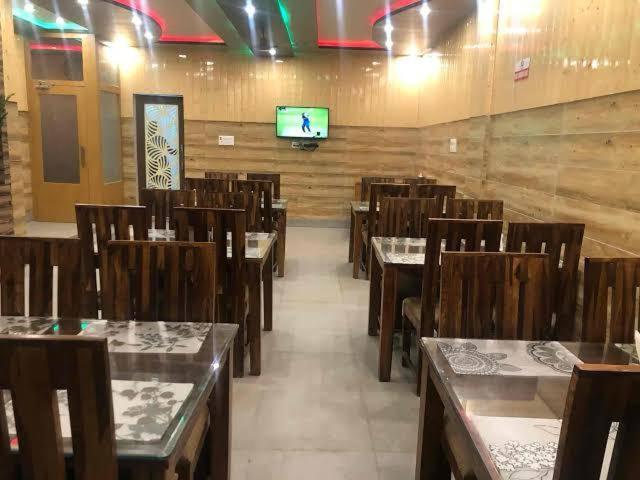 a dining room with tables and chairs and a television at Tara Hotel & Restaurant in Kallar