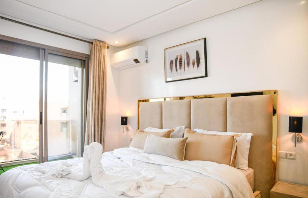 a bedroom with a large bed with a large window at Appart luxe arya in Fès