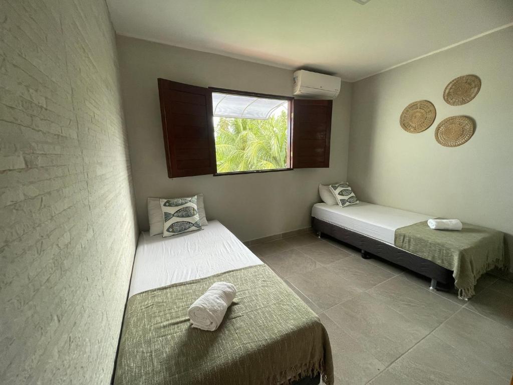 Una pequeña habitación con dos camas y una ventana. en Casa Valentina em Milagres - AL, en São Miguel dos Milagres