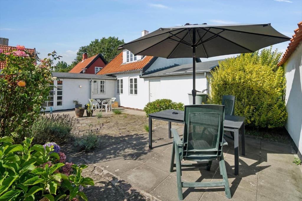a table and chair with an umbrella in a backyard at 4795-Ronne-Varpelokken-9 in Rønne