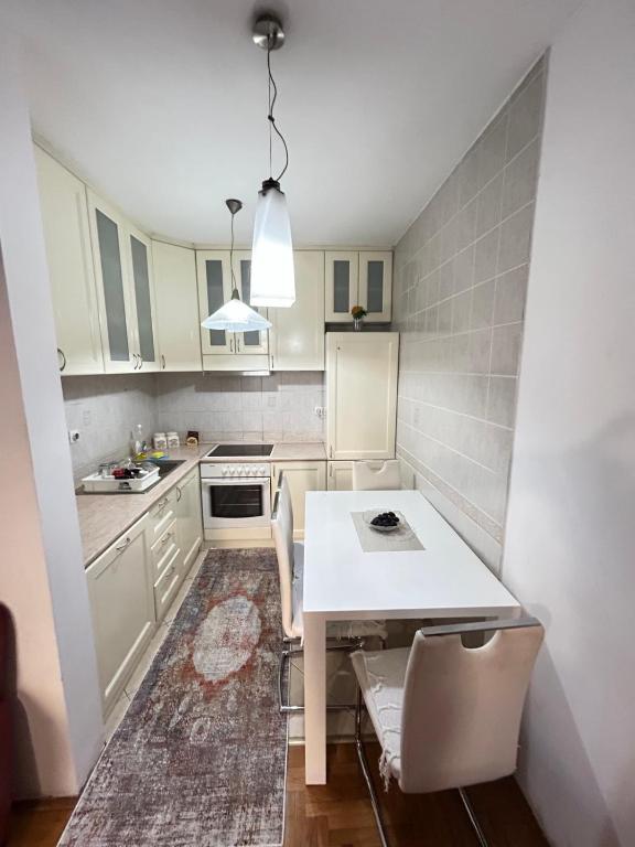 a kitchen with white cabinets and a table and chairs at Milenijum in Podgorica