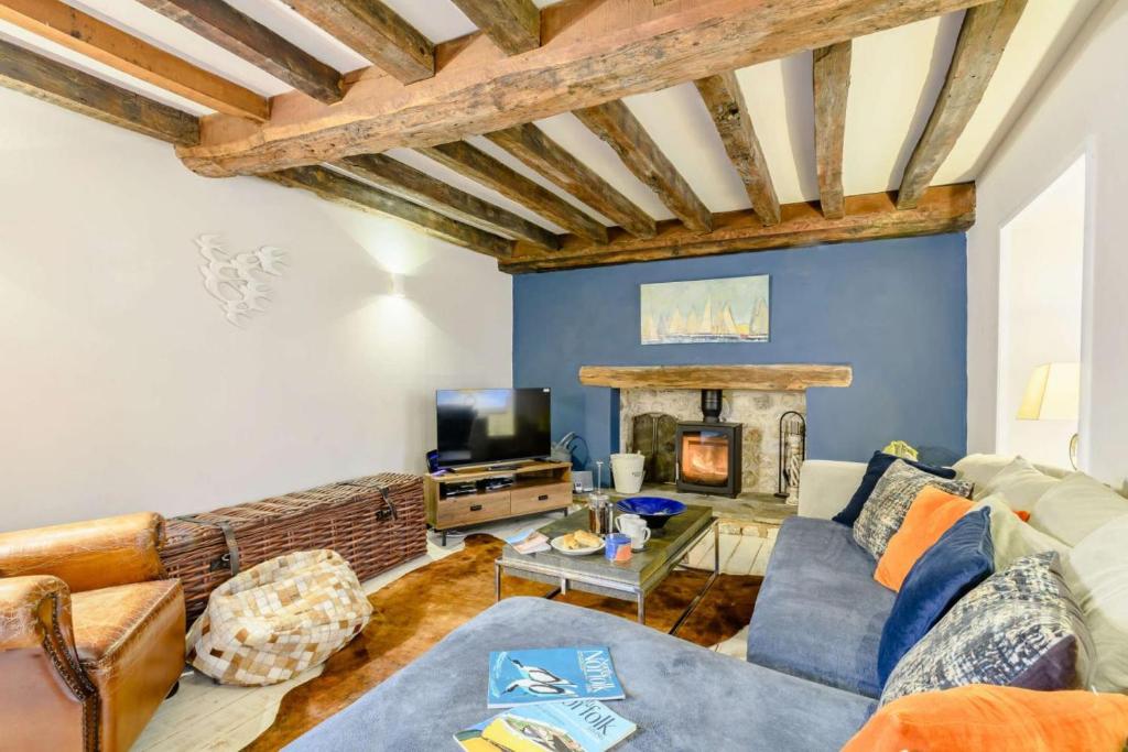 a living room with a couch and a fireplace at Hemingford Cottage in Brancaster