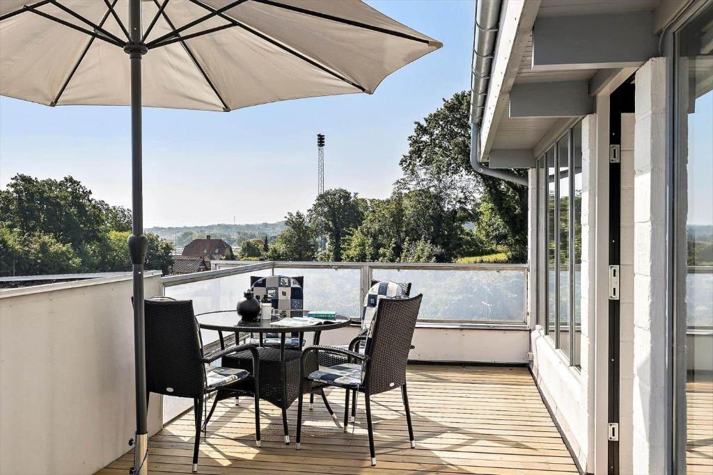 Un patio con una mesa y sillas y una sombrilla. en 6760-Allinge-Tejnvej-84-lejl-5, en Allinge