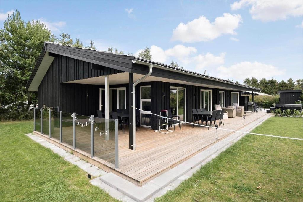 a black house with a wooden deck in a field at OH438-Hadsund-Sellegaarde-Vest-16-A in Hadsund