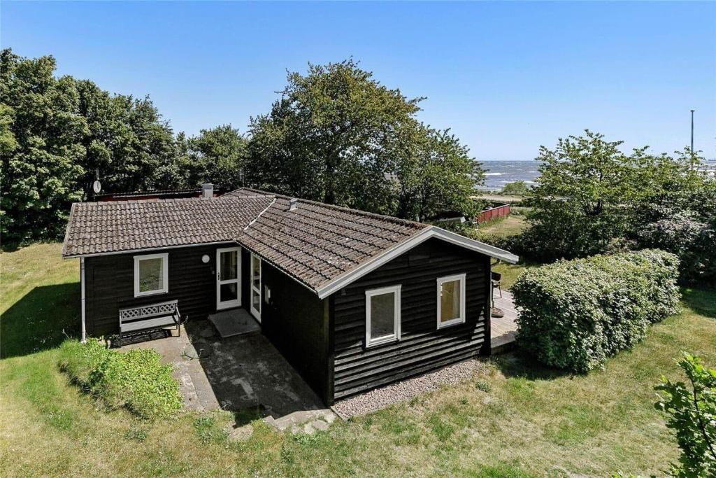 una pequeña casa negra en un campo con árboles en 3663-Nexo-Strandvolden-3, en Neksø