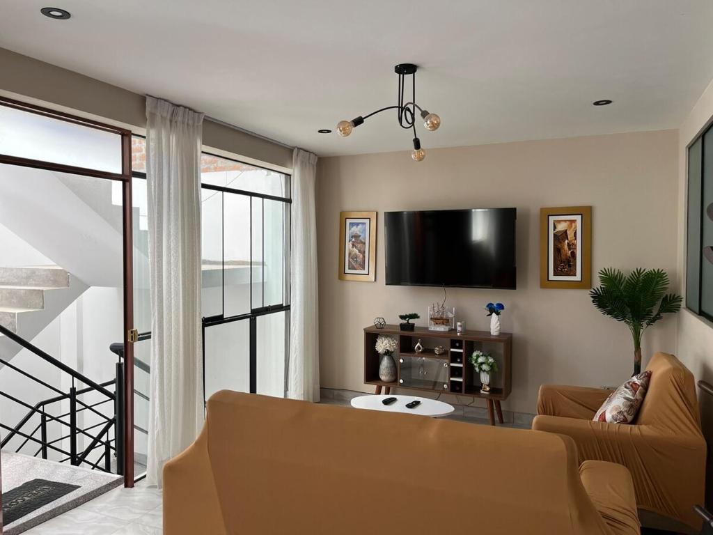 Una sala de estar con un sofá y un televisor de pantalla plana. en Departamento de Estreno Amplio y Confortable, en Ayacucho