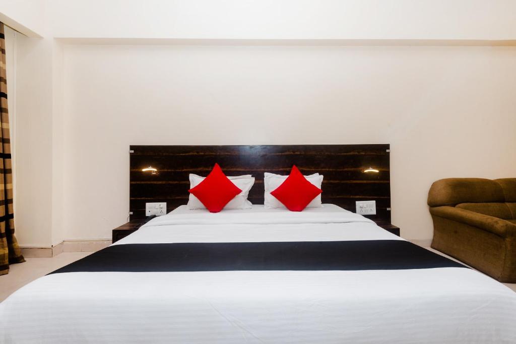 a bedroom with a large white bed with red pillows at Hotel O Sai Plaza in Kalyan