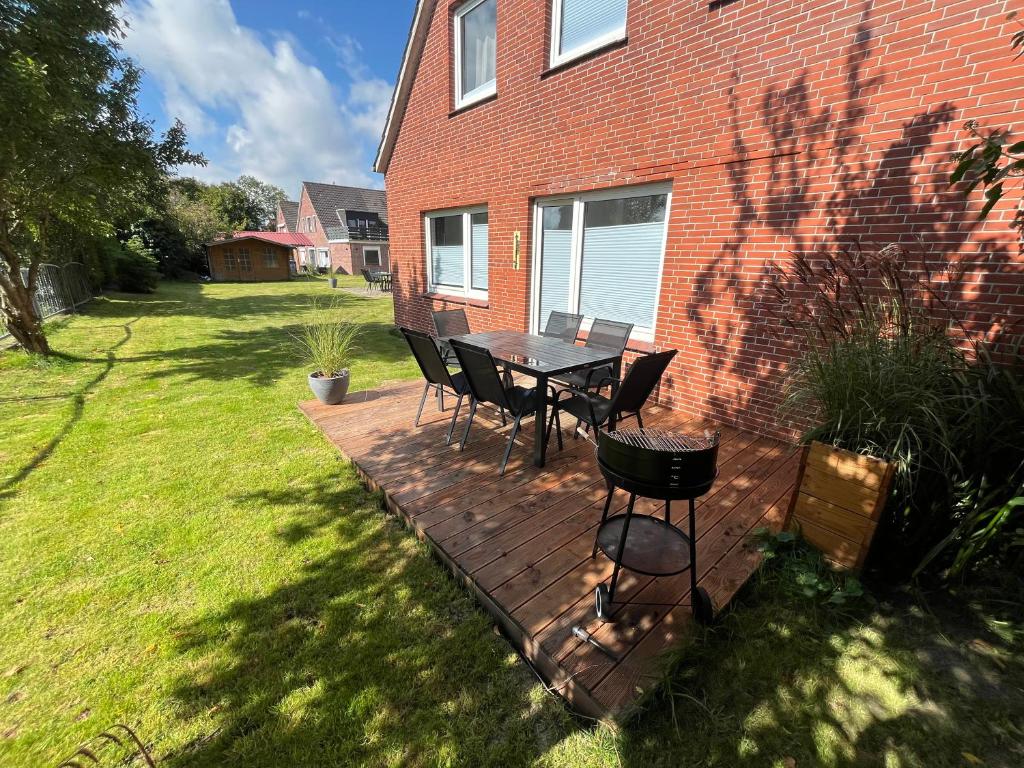 a patio with a table and chairs in a yard at Vier Nordlichter Erdgeschosswohnung mit Terrasse und Garten in Bensersiel