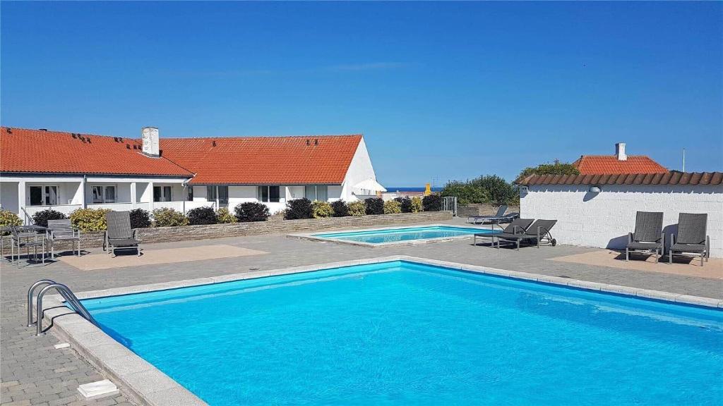 a large blue swimming pool in front of a house at 5505-Gudhjem-Kirkevej-10-Lejl-20 in Gudhjem