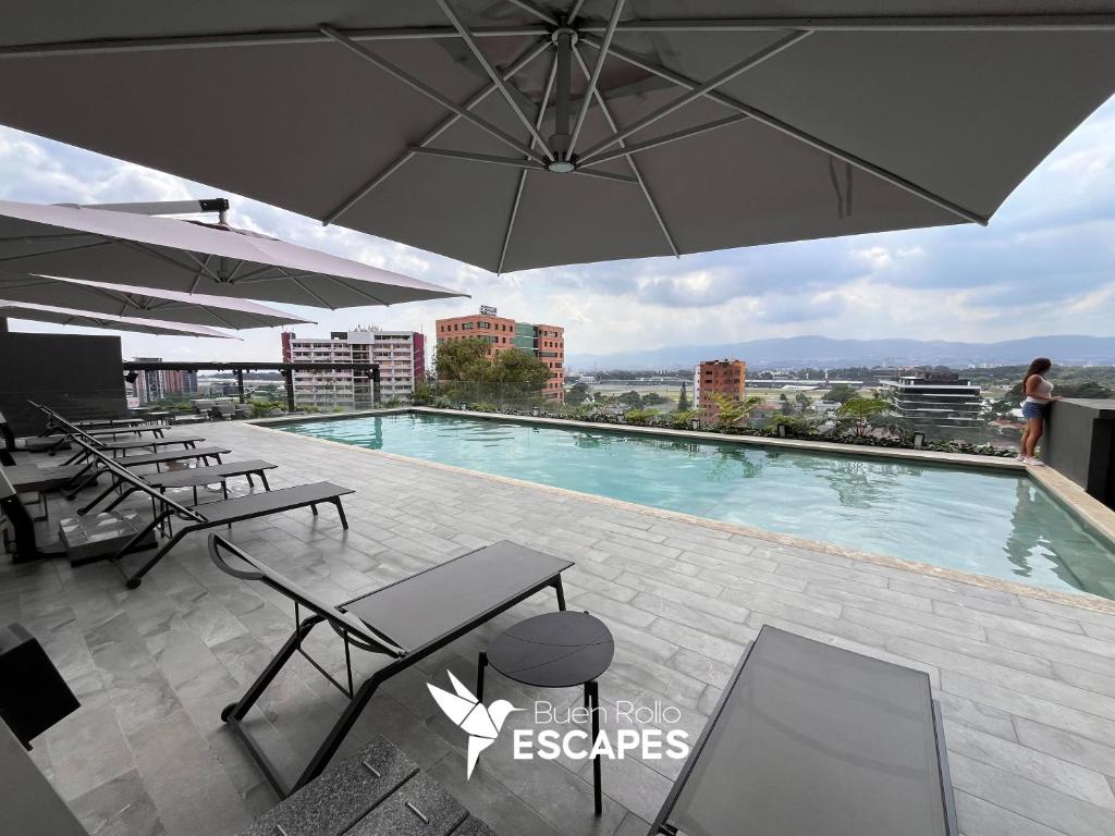 a swimming pool on top of a building with an umbrella at Luxury High-Floor 3 Bedroom Apartment FREE Pool & Gym in Guatemala