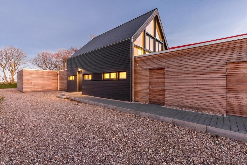 a house with a black roof and wooden walls at Haus Berta Exklusives Architektenhaus Fehmarn, strandnah in Fehmarn