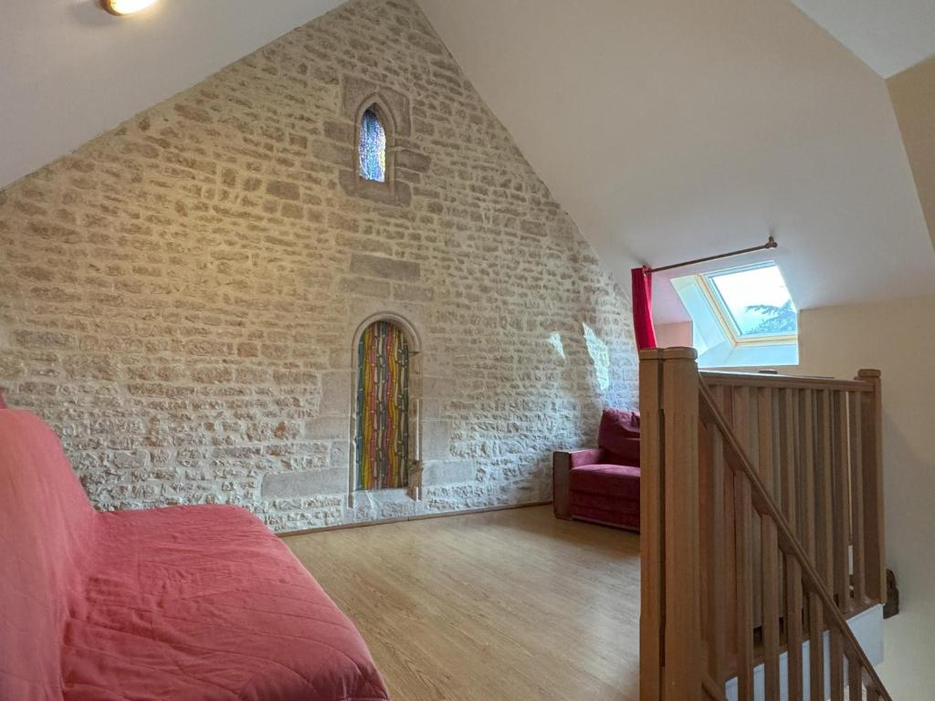 a bedroom with a brick wall with a bed and a staircase at Domaine Saint Jean in Saint-Côme-du-Mont