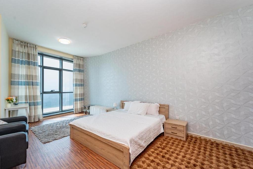 a bedroom with a bed and a large window at Luxury Oceanfront Fully Furnished 2BR! in Ajman 