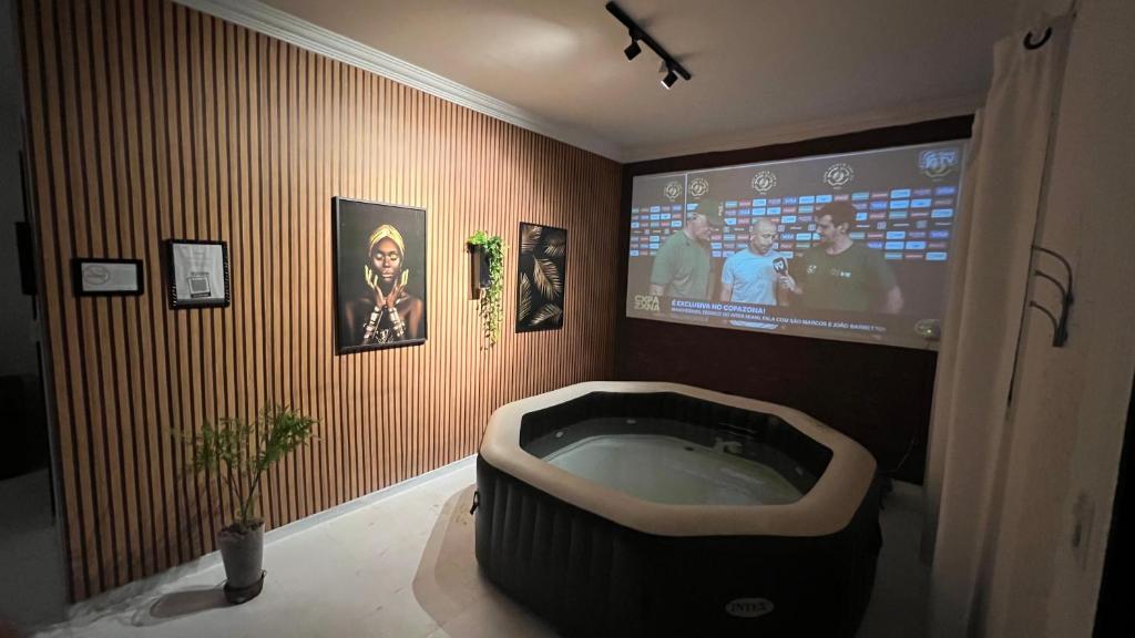 a bathroom with a tv and a bath tub at Casa No Centro de Caldas Novas in Caldas Novas