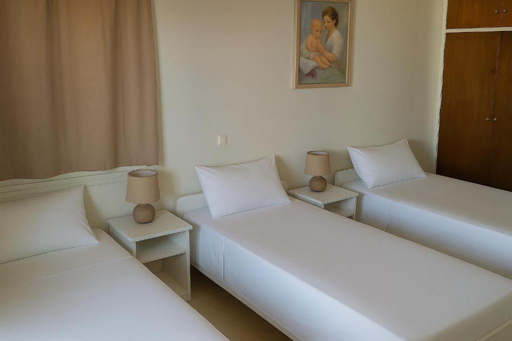 two beds in a room with white sheets at NAFPAKTOS APARTMENT, STUDIOS AND ROOMS iN PORT in Nafpaktos