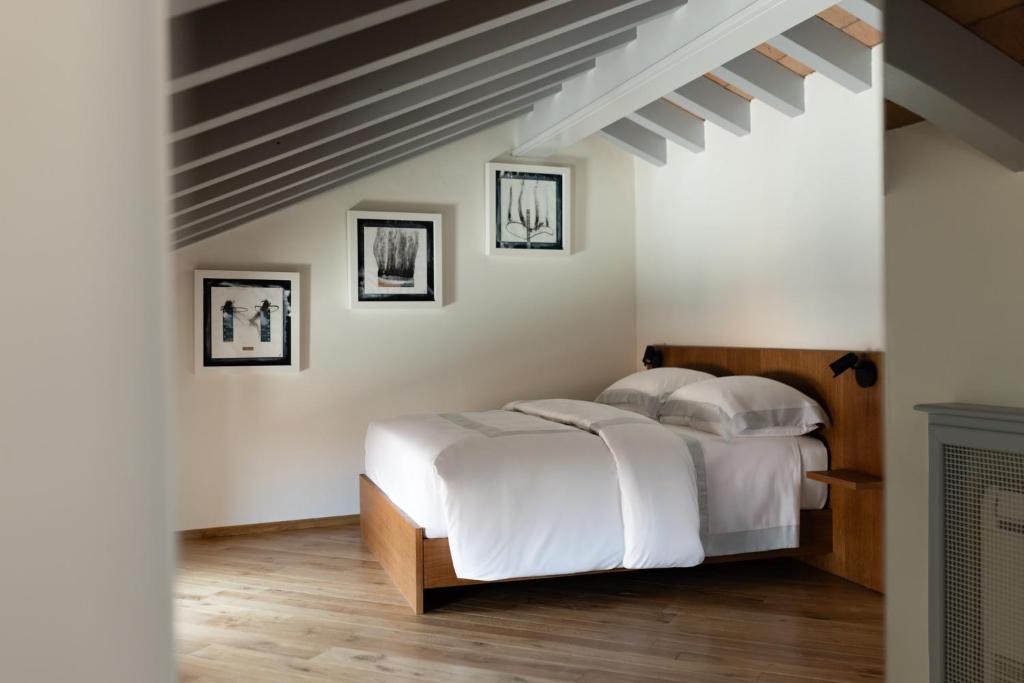a bedroom with a bed with white sheets and wood floors at Dé Corner Rooms and Suites in Soncino