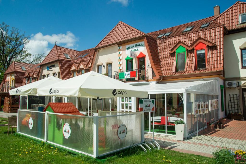 un restaurant avec des parasols en face d'un bâtiment dans l'établissement Villa Bella Italia, à Mikołajki