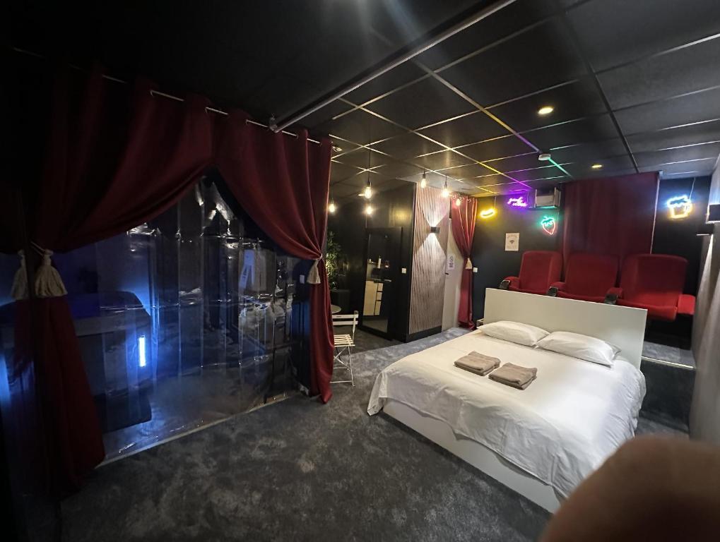 a bedroom with a white bed and red chairs at Cocon Jacuzzi et cinéma 4K B in Bordeaux