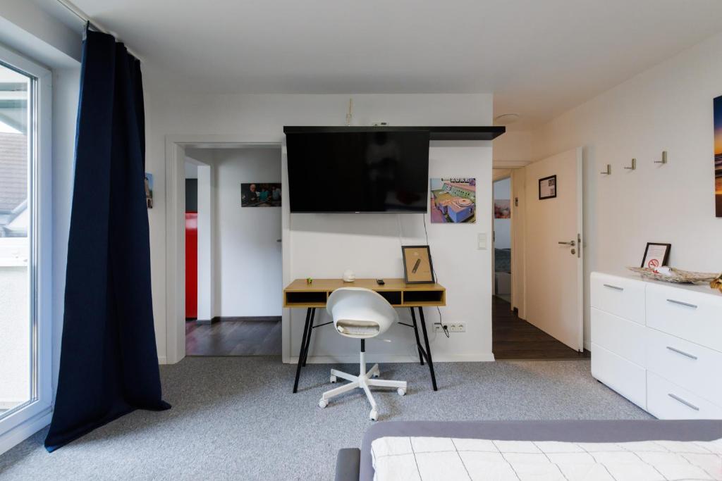 a bedroom with a desk and a tv on a wall at Gemütliche Studio im Zentrum von Bad Hersfeld mit Küche und Balkon "Zuse" in Bad Hersfeld