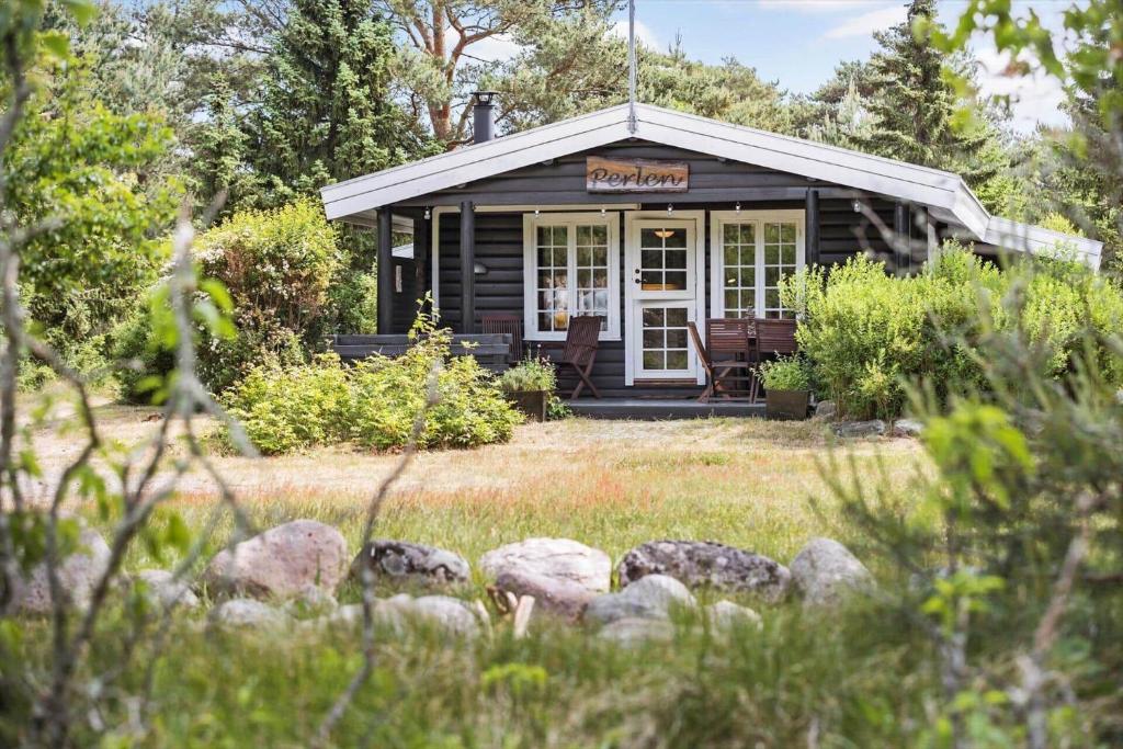 a log cabin with a porch and chairs in a yard at 1444-Aakirkeby-Poseregardsvejen-15 in Vester Sømarken