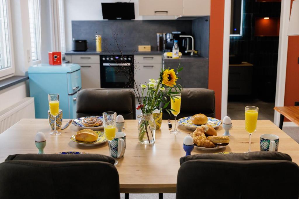 a wooden table with food and glasses of orange juice at "Badestube Loft" im Zentrum von Bad Hersfeld mit modernem Design und offenem Wohnkonzept in Bad Hersfeld