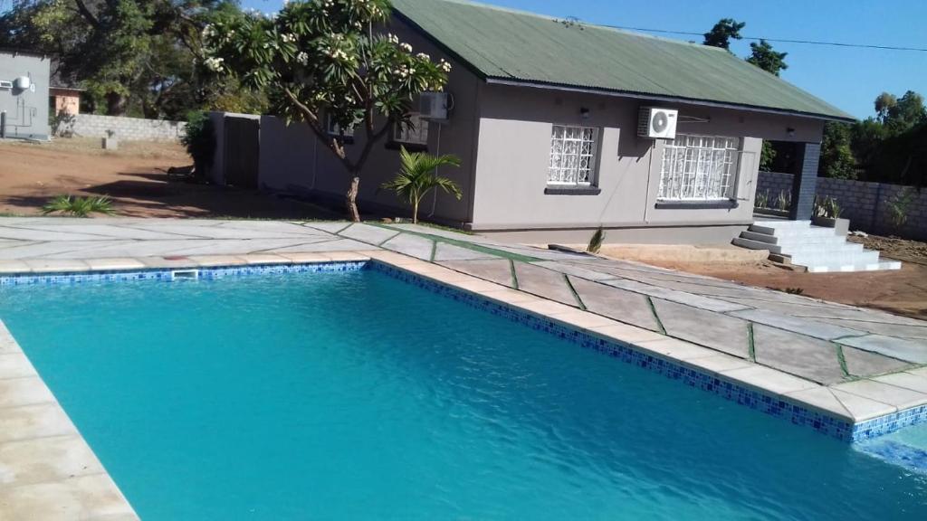 a swimming pool in front of a house at Yeta Apartments in Livingstone