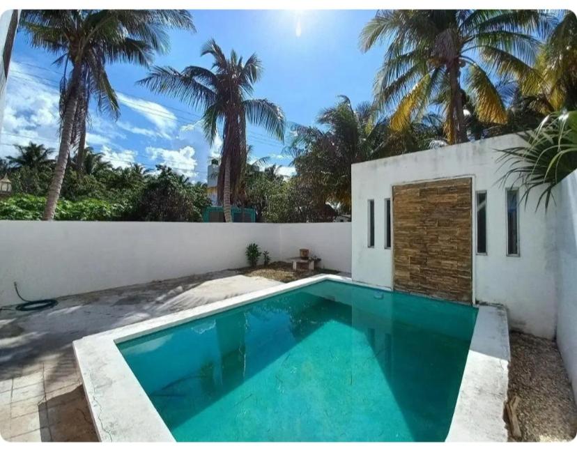 a swimming pool in front of a house with palm trees at 1 Minute Walk to the Beach! in Telchac Puerto