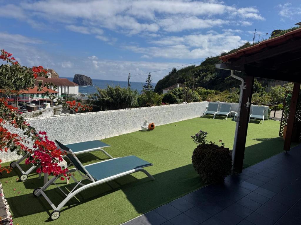a patio with lounge chairs and a grass yard at Villa Matilde e Joaquim in Porto da Cruz